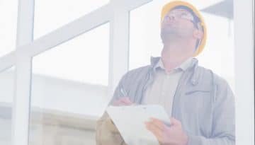 Male supervisor looking up while writing on clipboard in office